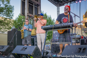 Keyboard and guitar player Scotty Wenzel, trombone player Zach Dinges and saxophone player Alex Toepfer performing Live on Mass in downtown Lawrence, KS on June 29, 2018.