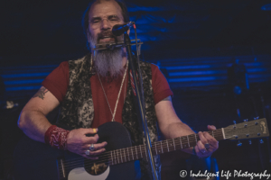 Steve Earle in concert on the harmonica and acoustic guitar at Knuckleheads Saloon in Kansas City, MO on July 9, 2021.