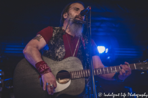 Steve Earle singing and playing the harmonica and acoustic guitar at Knuckleheads Saloon in Kansas City, MO on July 9, 2021.